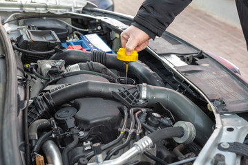 Man checking oil level in car engine.
