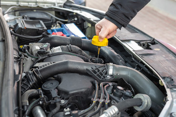 Man checking oil level in car engine.