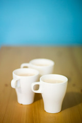 Fototapeta na wymiar background with three white coffee cups, milk drink, top view