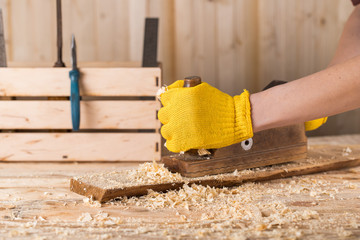 Close up of a carpenter planing a plank of wood with a hand plane