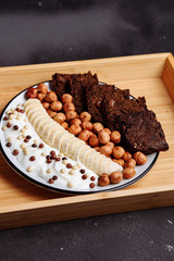 Healthy breakfast with delicious bread, banana, hazelnut and yogurt in bowl