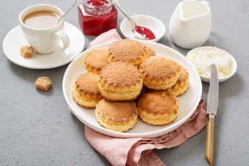 Traditional British Scones with clotted cream, strawberry jam and a cup of coffee.