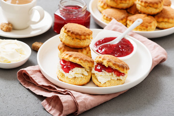 Traditional British Scones with clotted cream, strawberry jam and a cup of coffee.