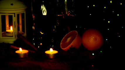 Christmas lights flicker at the holiday table. The candle burns and is reflected in glasses with...