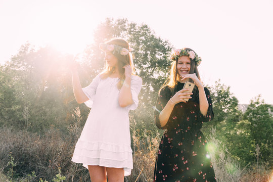 Two young girls hug during sunset in the field with wine glasses friendship concept copy space