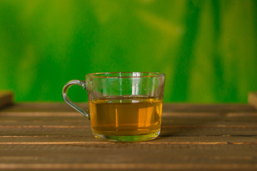 Glass Cup of tea on a wooden table. Green background.
