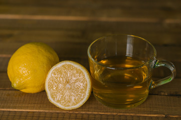 Glass Cup and lemons with tea on wooden table. Prevention of colds. Healthy diet.