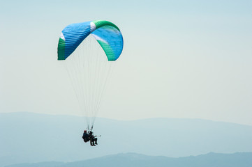 Paraglider fly over a mountain valley on a sunny summer day. Paragliding in the Carpathians in the summer.