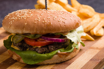 tasty rustic hamburger with fries on wooden table