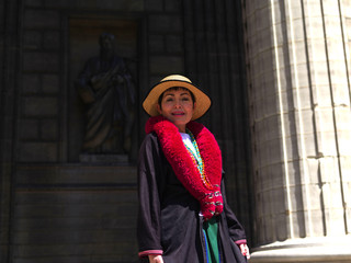 Femme en manteau noir et écharpe rouge devant l'église de la Madeleine à Paris