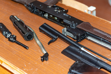 Kalashnikov assault rifle disassembled on a table at military exercises.