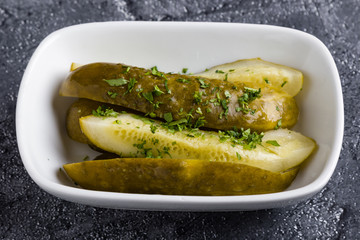 salted sour pickles with herbs in white bowl