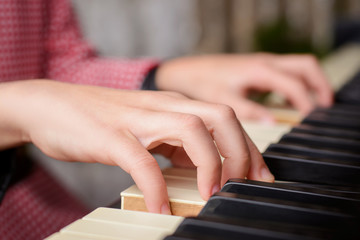 Obraz premium Close up photo of hands of a small talented girl playing the piano at home, performing classical music at home, getting ready to the cllasses in the music school