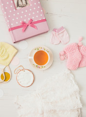 Using herbal breastfeeding tea to increase breast milk production for mothers concept. Different baby things with cup of tea on light white wooden board background, flat lay view studio composition