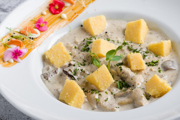 chicken with mushrooms sauce and polenta cubes in white table