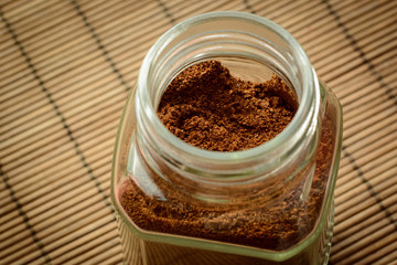 Ground coffee in a glass jar on a brown bamboo background