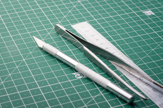 Scalpel, tweezers, ruler on cutting mat