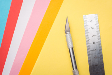 Scalpel and ruler on colourful background of coloured papers