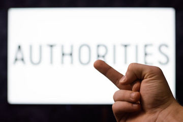 Male`s hand showing middle finger sign to screen with inscription AUTHORITIES