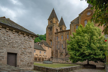 Fototapeta na wymiar Fountain and arcade in the interior courtyard of the Conques monastery