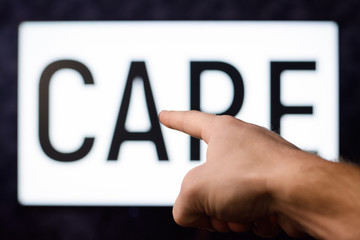 Man points to the screen with inscription CARE