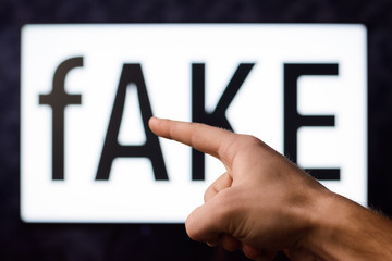 Pointing to screen with inscription fAKE in order to show source of a real false