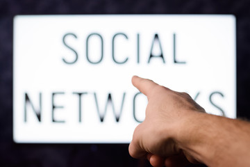 Man who is depending on social networks points to a screen with inscription SOCIAL NETWORKS