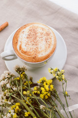 cup of coffee with chamomile flowers on linen background