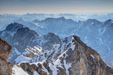Elevated view of snowy climbing route Jubilaumsgrat with jagged blue ridges of  Wetterstein and Karwendel mountains in morning haze, Bayerische Alpen Northern Limestone Alps Bayern Germany Europe