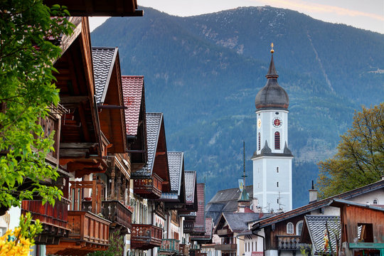 Row of typical German houses with wooden balconies in historic center of Garmisch with domed parish church St Martin and Wank mountain of Bavarian Prealps, Garmisch Partenkirchen Bayern Germany Europe