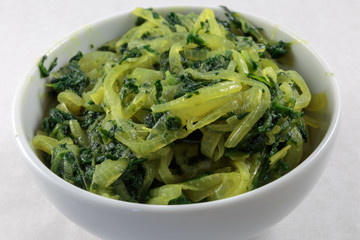 Stir fried spinach and onion. Concept of vegan food or garnish at least. White background.