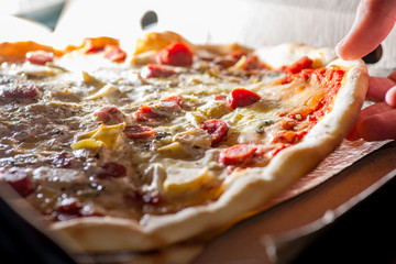  hand takes a slice of fresh pizza with  pulling  melted cheese out of the box. Food delivery