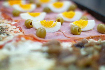 Pizza with hard boiled eggs and green olives.