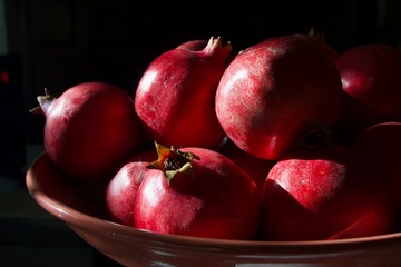 A whole scarlet pomegranate on a black background close-up.