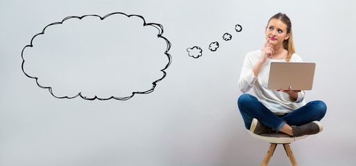 Blank speech bubble with young woman using her laptop on a grey background