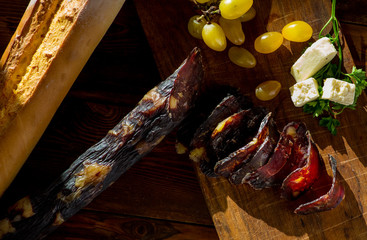thin slicing jerked sausage and other snacks on a wooden board