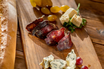 thin slicing jerked sausage and other snacks on a wooden board