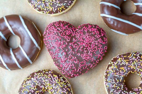 Mix donuts icing round shape and heart. Donuts strewed with decorative sprinkles top view