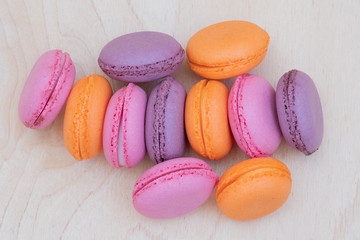 many colorful macaroons on a wooden background are folded into a composition as a blank for the designer