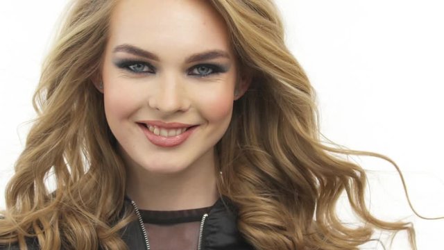 Beautiful smiling woman with a long blond hair. Happy fashion model with a stylish makeup.