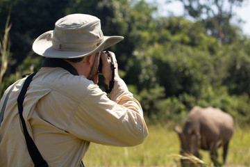 Safari man in grass with camera