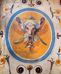 Face of fantasy person or faun on wall with fresco, inside 14th century Palazzo in Italy. Medieval art of Italy