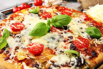 Vegetarian Italian pizza with melted cheese, red tomatoes and green basil on a table decorated by cheese, tomato and cherry tomatoes