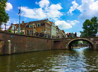 Fototapeta na wymiar Amazing view of beautiful buildings, bicycles, a bridge with group of people and tourist boats on Oudegracht (Old Canal). Utrecht, Netherlands