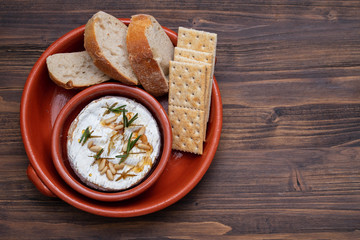 cheese with herbs, nuts and honey in ceramic dish