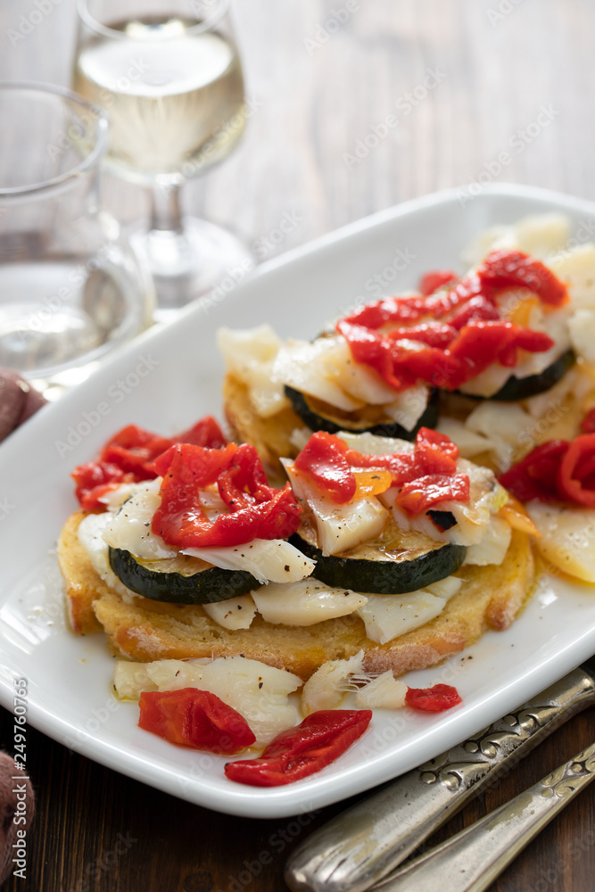 Poster corn bread with cod fish and courgette on white dish