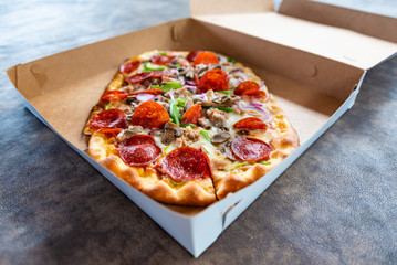 Pizza with several toppings in delivery box