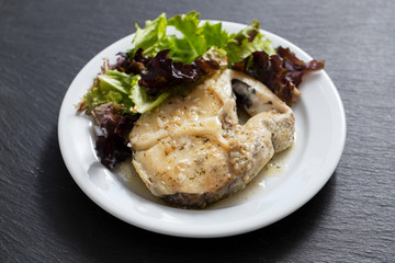 boiled fish with sauce and green salad on white plate
