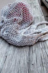 Gray string shopping bag with knitting yarn on old vintage style wood