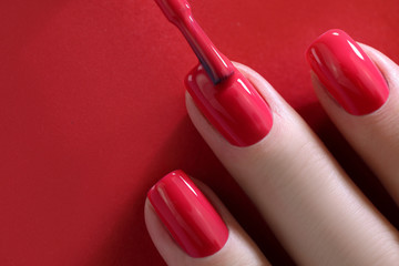 Red Finger nail point isolated red background with nail polish. Painting nails.